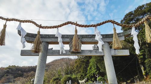 Low angle view of text hanging on rope against sky