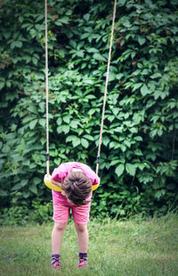 Full length of boy playing on swing at field