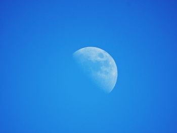 Low angle view of moon against clear blue sky