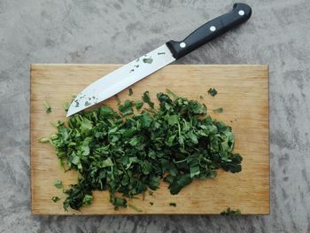 Directly above view of chopped cilantro by knife on cutting board