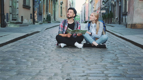 Friends sitting on street in city