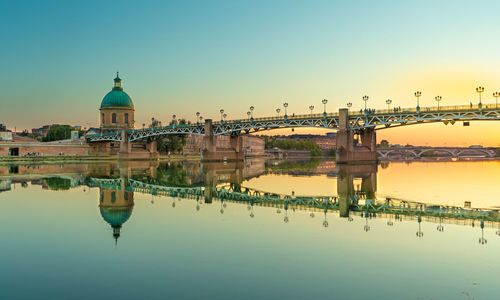 Reflection of building in lake against clear sky at sunset