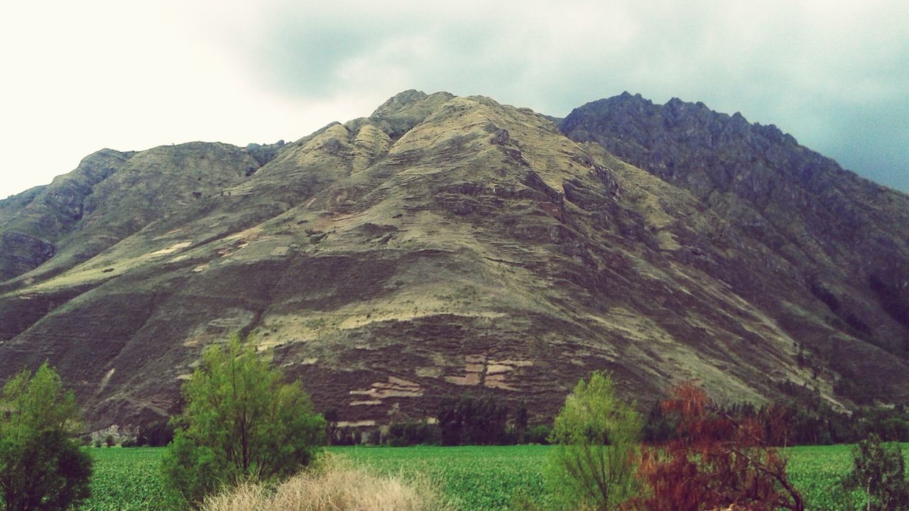 mountain, mountain range, sky, tranquility, tranquil scene, landscape, scenics, built structure, architecture, beauty in nature, grass, nature, green color, rock formation, non-urban scene, rocky mountains, history, hill, building exterior, day