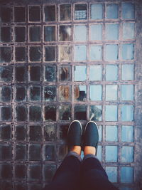 Low section of woman standing on glass footpath