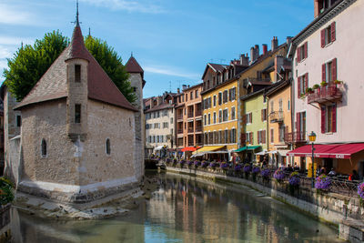 Buildings by river against sky