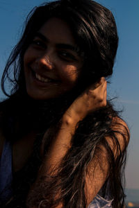 Portrait of woman smiling with long hair against blue sky