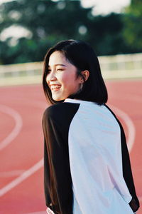 Smiling young woman standing on running track