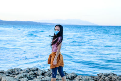 Woman standing at beach against sky