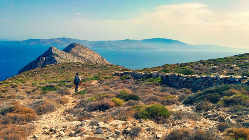 Rear view of man walking on mountains against sky