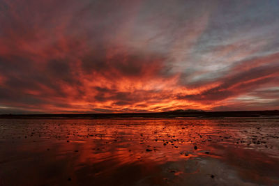 Scenic view of sea against dramatic sky during sunset