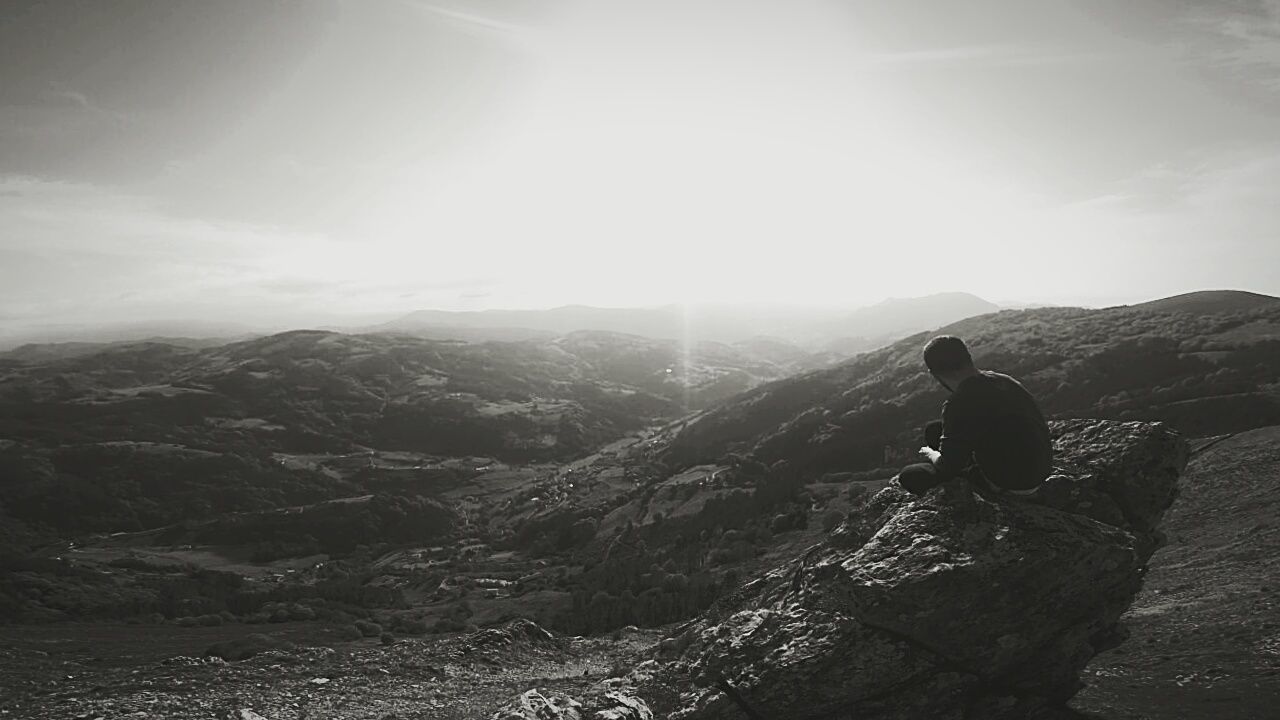 mountain, lifestyles, leisure activity, sun, men, tranquil scene, tranquility, sunlight, scenics, landscape, mountain range, sky, full length, rear view, beauty in nature, sunbeam, nature, lens flare