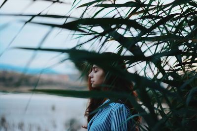 Young woman with eyes closed standing by plants