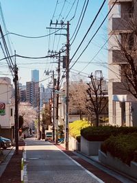 Road by buildings in city against sky