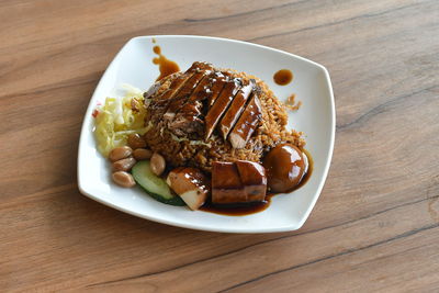 Braised duck rice served in plate on wooden table