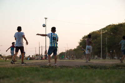 Group of people playing soccer on field against sky