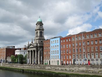 Buildings in city against cloudy sky