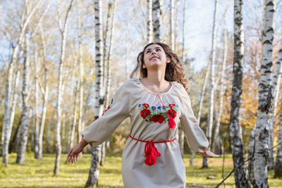 Beautiful woman in national ukrainian national traditional costume clothes dancing in forest