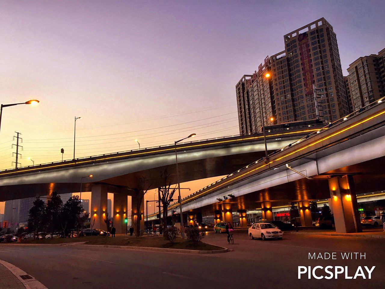 building exterior, transportation, architecture, built structure, city, illuminated, street, car, road, land vehicle, street light, mode of transport, sky, city life, text, city street, traffic, dusk, communication, outdoors