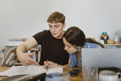 Man pointing at book while studying together