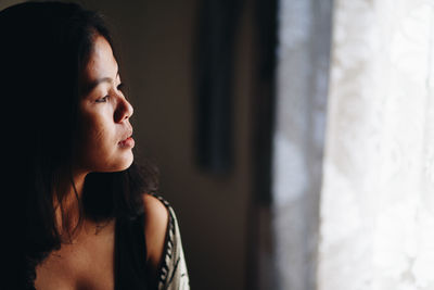 Thoughtful mid adult woman looking away at home