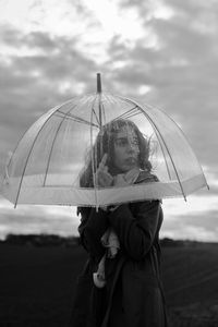 Woman holding umbrella while standing against sky