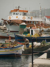 Fishing boats moored at harbor against sky