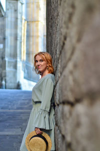 Portrait of young woman standing by wall