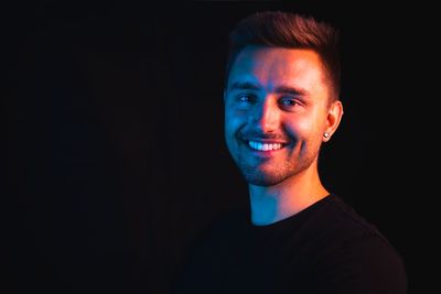 Portrait of young man against black background