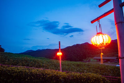 Illuminated lantern on field against sky at dusk