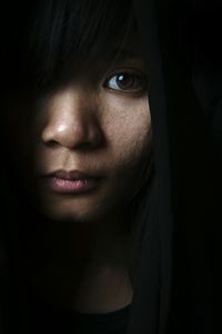 Close-up portrait of young woman in dark
