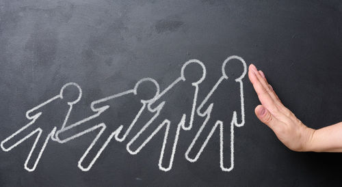 Cropped hand of person with text on blackboard