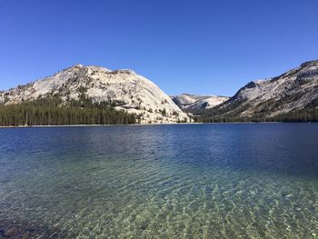 Scenic view of lake and mountains against clear blue sky