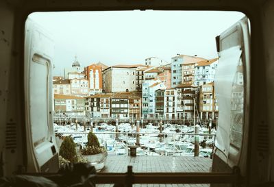 Buildings against sky seen through glass window