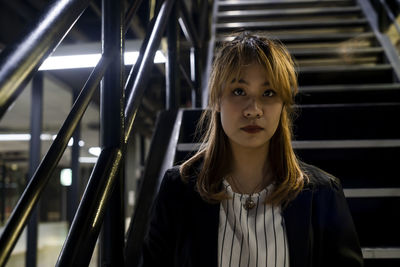 Portrait of businesswoman sitting on steps at railroad station