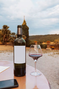 Wine glass bottle on table against sky
