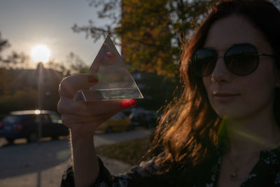 Close-up portrait of woman holding crystal in city during sunset