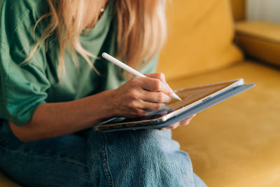 Close-up of an unrecognizable woman drawing with a stylus in an app on a tablet.