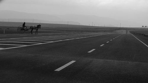 People riding horse on road against sky