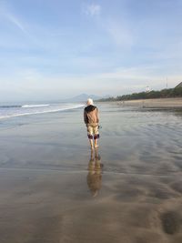 Rear view of woman on beach against sky