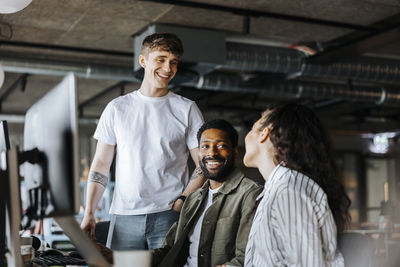Smiling male entrepreneurs talking with female colleague at office