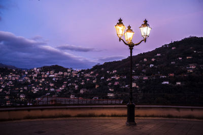 Illuminated street light against sky at night