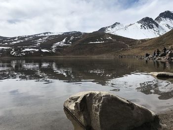 Scenic view of lake by snowcapped mountains against sky