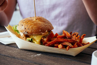 Midsection of person having burger and french fries on restaurant table