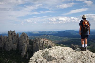 Rear view of hiker standing on cliff against mountain