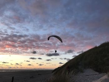 Person paragliding against sky during sunset