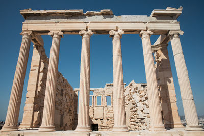 Low angle view of historic columns against clear sky