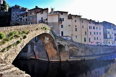 Bridge over river in city against clear sky