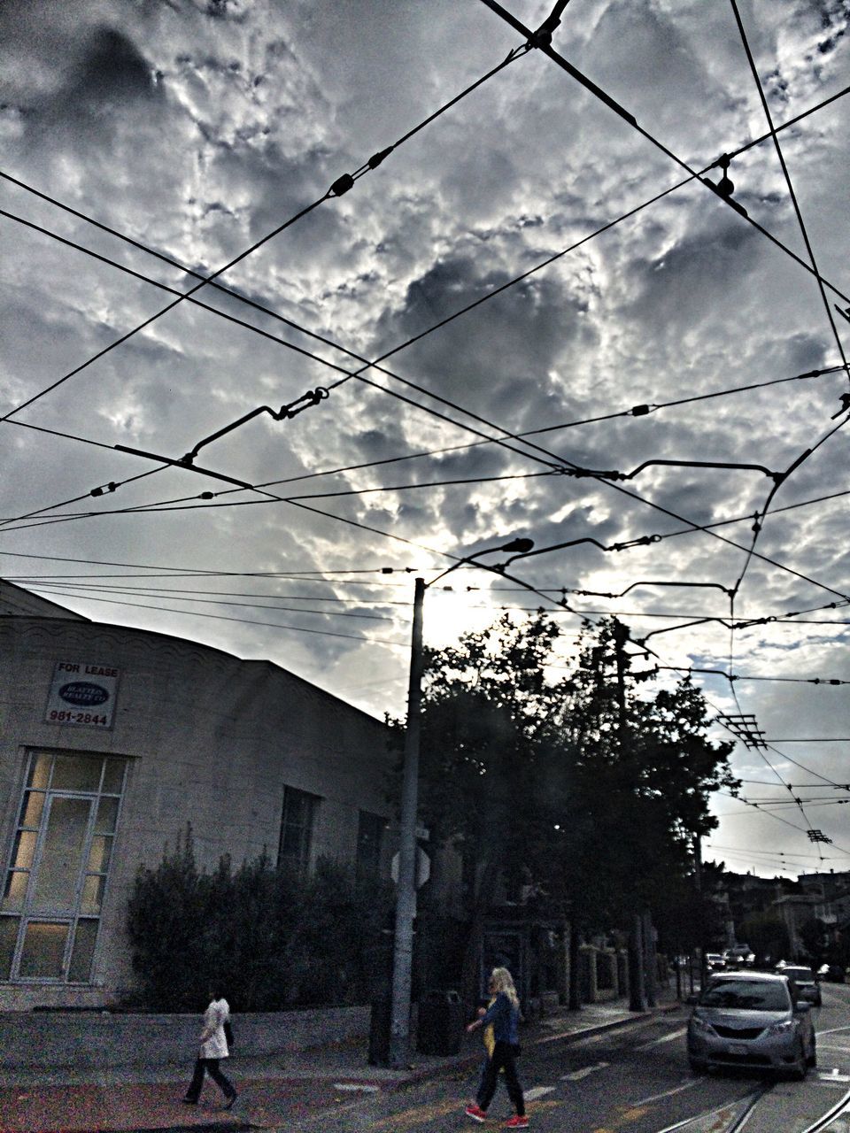 sky, power line, building exterior, men, cloud - sky, architecture, built structure, transportation, street, electricity pylon, lifestyles, cable, cloud, cloudy, walking, person, leisure activity, full length