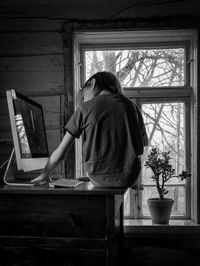Rear view of man sitting on table at home