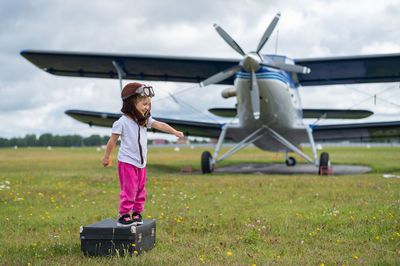 Full length of girl standing against airplane